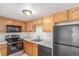 Kitchen with wood cabinets, black appliances, and neutral countertops at 9725 E Harvard Ave # 317, Denver, CO 80231