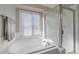 Bathroom featuring a shower with glass door and tub, complemented by a window for natural light at 20898 E Hamilton Ave, Aurora, CO 80013