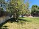 Backyard with lush green grass, mature trees, and a wooden fence around the property at 4609 S Kalispell Way, Aurora, CO 80015