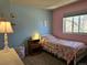 Bright bedroom with blue and pink walls, window, and hardwood nightstand at 4609 S Kalispell Way, Aurora, CO 80015