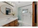 Bright bathroom featuring a sleek vanity, round mirror, and walk-in shower with safety bars at 7563 Lamar Ct, Arvada, CO 80003