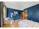 Stylish blue bedroom featuring natural hardwood floors, a comfortable chair, and natural light at 7563 Lamar Ct, Arvada, CO 80003