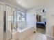 Main bathroom showcasing a glass-enclosed shower, soaking tub, tile floors and a glimpse into the main bedroom at 11811 Lewiston St, Commerce City, CO 80022