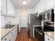 Efficient kitchen featuring stainless steel appliances, white cabinets, and wood flooring at 3742 S Granby Way, Aurora, CO 80014