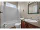 Cozy bathroom with tiled shower-tub, framed mirror, and wooden vanity at 15616 Soo Line Way, Monument, CO 80132