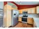 Kitchen with wood cabinets, stainless steel appliances, and red painted accent wall at 16641 Martingale Dr, Parker, CO 80134