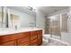 Bathroom featuring double vanity with wood cabinets, light countertop, and glass enclosed shower at 13684 Lilac St, Thornton, CO 80602