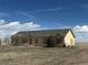 Single-story home with weathered exterior, set against a blue sky with scattered clouds at 5500 Dacono Ct, Byers, CO 80103