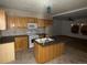 Functional kitchen featuring wood cabinets, an island with sink, and white appliances at 5500 Dacono Ct, Byers, CO 80103