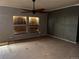 Empty living room featuring a ceiling fan, plywood covered windows, and neutral walls at 5500 Dacono Ct, Byers, CO 80103