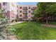 Backyard view of an apartment complex showcasing large lawn and mature trees with multiple floors and balconies at 3401 Arapahoe Ave # 105, Boulder, CO 80303