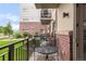 Private balcony with black metal railing, table, and chairs overlooking a tranquil community green space at 3401 Arapahoe Ave # 105, Boulder, CO 80303