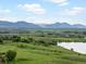 Scenic aerial view of lush green landscapes, a tranquil lake, and majestic mountains in the distance at 10954 W 100Th Way, Broomfield, CO 80021