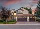 Charming two-story home with a three-car garage and stone accents, set against a beautiful sunset sky at 10954 W 100Th Way, Broomfield, CO 80021