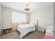 Cozy bedroom with a white bed, a ceiling fan, and a large window letting in natural light at 7154 E 131St Pl, Thornton, CO 80602