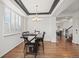 Elegant dining room with a tray ceiling, shuttered windows, hardwood floors, and stylish lighting fixtures at 7154 E 131St Pl, Thornton, CO 80602