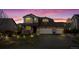 Twilight front exterior features a stone facade, well-lit landscaping, and a three-car garage, enhancing curb appeal at 7154 E 131St Pl, Thornton, CO 80602
