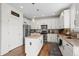 Bright kitchen features white cabinetry, stainless steel appliances, an island, and hardwood floors at 7154 E 131St Pl, Thornton, CO 80602