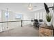 Upstairs office space with a desk and dual monitors, a ceiling fan, and a railing overlooking the floor below at 7154 E 131St Pl, Thornton, CO 80602