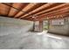 Unfinished basement with exposed wood ceiling, concrete walls, and outside access, perfect for storage or future customization at 3611 N Vine St, Denver, CO 80205
