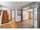 View of basement area with wooden stairs, wood-look flooring, brick accent wall, access to other rooms, and exposed ductwork at 3611 N Vine St, Denver, CO 80205