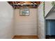 Unfinished basement space with exposed ceiling, wood-look floors, textured walls, and natural light from a small window at 3611 N Vine St, Denver, CO 80205