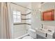 White tiled bathroom with tub/shower, patterned tile stripe, and unique round mirror set at 3611 N Vine St, Denver, CO 80205