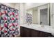 Bathroom featuring dual sinks with marble countertops, a large mirror, and a decorative shower curtain at 2906 E 163Rd Ave, Thornton, CO 80602