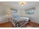 Bright bedroom featuring wood floors, a patterned quilt, and two sunny windows at 11707 W 65Th Cir, Arvada, CO 80004