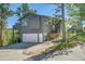 Two-story home exterior with a garage, a wooden deck, a garden, and ample parking in a lush, mountain setting at 30273 Conifer Rd, Evergreen, CO 80439