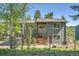 Charming gray two-story home with a wooden deck and a small garden, surrounded by lush greenery and tall trees at 30273 Conifer Rd, Evergreen, CO 80439