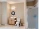 A neutral toned bathroom with a glass door shower and round mirror and neutral tiling at 12745 Uinta St, Brighton, CO 80602