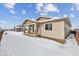 Tan house exterior with covered patio and snowy yard at 3254 Boral Owl Dr, Brighton, CO 80601