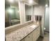 Modern bathroom featuring granite countertops, a white vanity, large mirror, and a jetted tub in the background at 7255 E Quincy Ave # 309, Denver, CO 80237