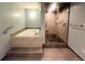Modern bathroom featuring a luxurious jetted tub and a glass-enclosed shower with unique stone pebble floor at 7255 E Quincy Ave # 309, Denver, CO 80237