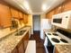 Galley kitchen with granite countertops, stainless steel sink, white appliances and wooden cabinetry for a modern, efficient space at 7255 E Quincy Ave # 309, Denver, CO 80237
