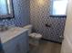 Stylish powder room features patterned wallpaper, a modern vanity with a sink, and a toilet at 1153 Elbridge Dr, Elizabeth, CO 80107