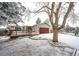 Charming home featuring a spacious wooden deck, red garage door and snow-covered front yard with mature trees at 4274 S Fundy Way, Aurora, CO 80013