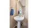 Bathroom with pedestal sink, chrome fixtures, and wall mirror with a tan wall color at 20414 E 55Th Pl, Denver, CO 80249