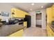 Efficient kitchen area with yellow cabinets, black appliances, and a convenient laundry area nearby at 20414 E 55Th Pl, Denver, CO 80249