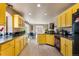 Well-equipped kitchen with yellow cabinets, sleek black countertops, and a view into the dining area at 20414 E 55Th Pl, Denver, CO 80249
