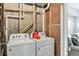 Functional laundry area with a modern washer and dryer setup, next to unfinished utility wall and partial drywall at 15295 W 68Th Pl, Arvada, CO 80007