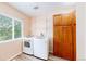 Functional laundry room with modern washer and dryer, storage cabinets, and natural light from the window at 7270 Marmot Ridge Pl, Littleton, CO 80125