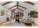 Cozy living room featuring exposed beams, a brick fireplace, and stylish modern furniture at 8132 Lodgepole Trl, Lone Tree, CO 80124