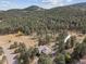 Aerial view of a home nestled among a lush pine forest landscape with rolling hills at 30444 Ruby Ranch Rd, Evergreen, CO 80439