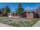 A single-story brick home with a manicured lawn and mature trees creating a cozy aesthetic at 8325 Elati St, Denver, CO 80221