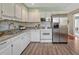 Bright kitchen features white cabinets, stainless steel appliances, granite counters and wood-look flooring at 8325 Elati St, Denver, CO 80221
