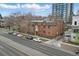 Three-story brick apartment building on a tree lined street with parked cars and a tall building in the background at 3132 E 17Th Ave # B, Denver, CO 80206