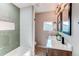 Bathroom featuring green subway tile in the shower, a double vanity, and modern light fixtures at 280 Birch St, Bennett, CO 80102
