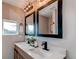 Updated bathroom featuring a double vanity with black fixtures and modern farmhouse lighting at 280 Birch St, Bennett, CO 80102